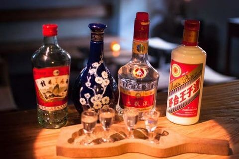 Selection of four bottles of Baijiu with glasses in the foreground.