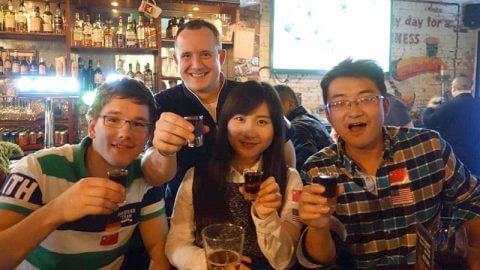 Students cheering with glasses of Baijiu at a bar in Shanghai